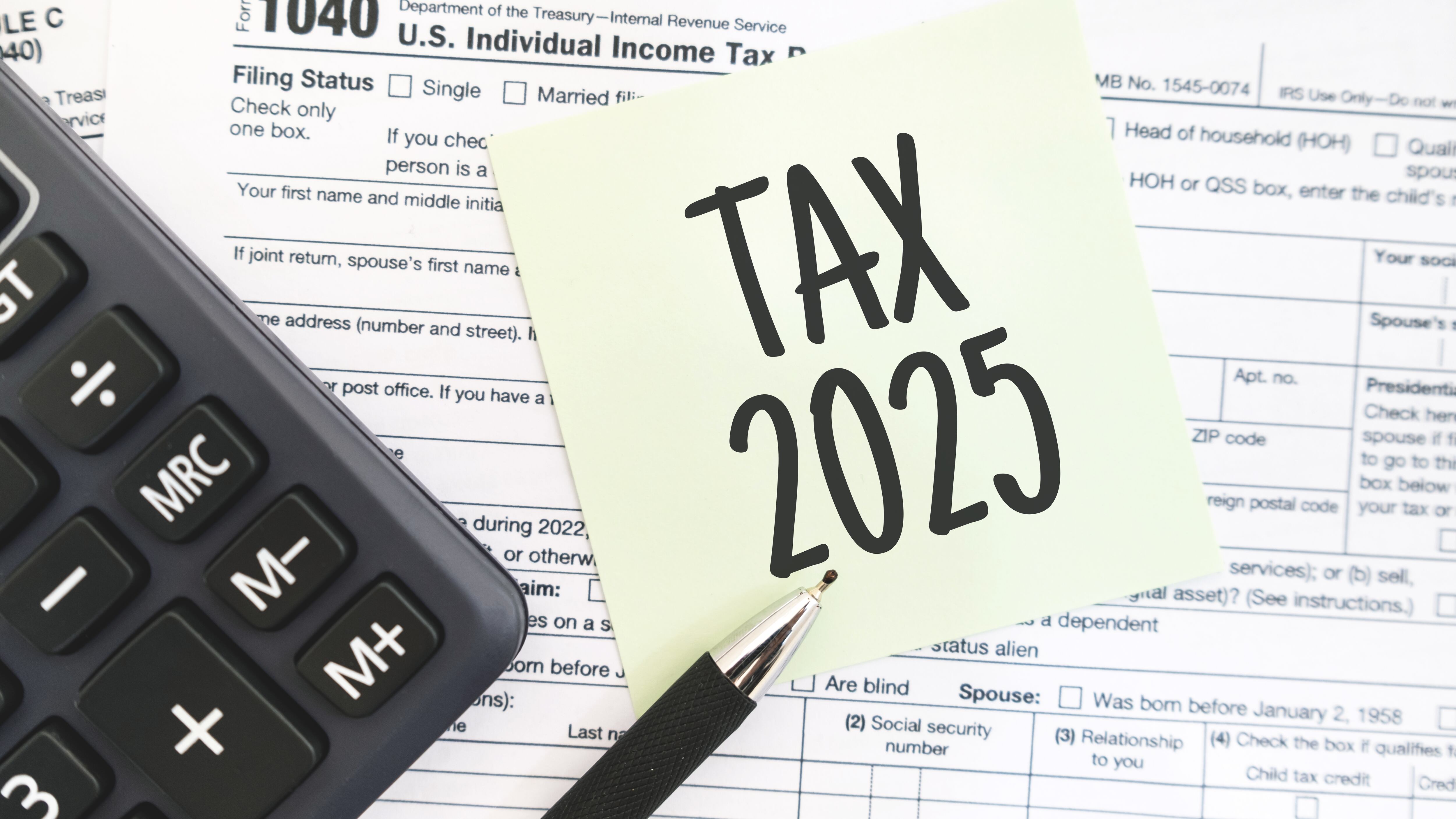 Text Tax 2025 on the note paper with calculator and taxes documents. Business and Annual tax concept.